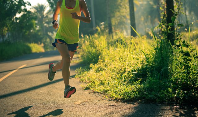 Personne faisant de la course à pied sur une rue asphaltée, entourée de verdure