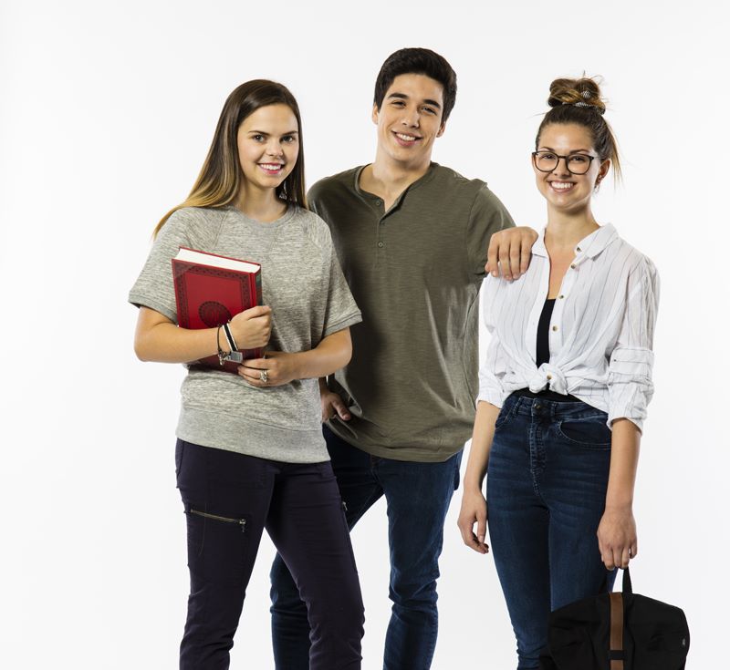 Deux étudiantes et un étudiant, debout et affichant un sourire