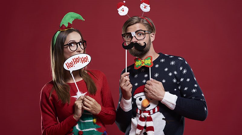 Jeune femme et jeune homme en chandails de Noël faisant des mimiques rigolotes