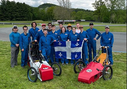 L'équipe gagnante de la compétition Électrathon 2024 du Cégep Limoilou, entourant leurs véhicules électriques, avec le drapeau du Québec devant eux