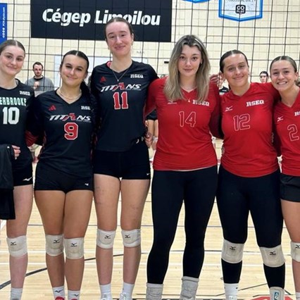 Les joueurses sont alignées sur le terrain de volleyball et sourient à la caméra.