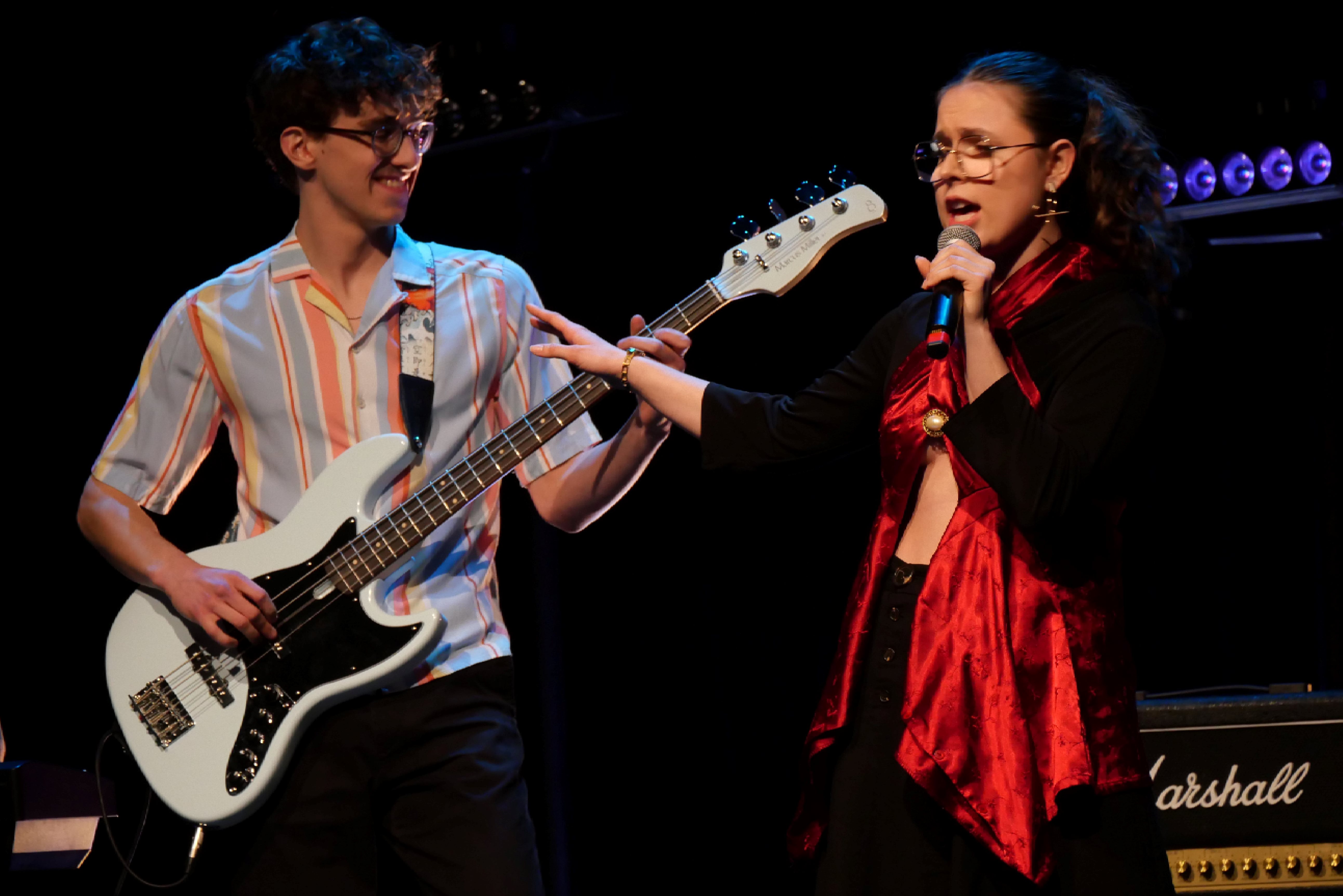 Un guitariste et une chanteuse sur scène.