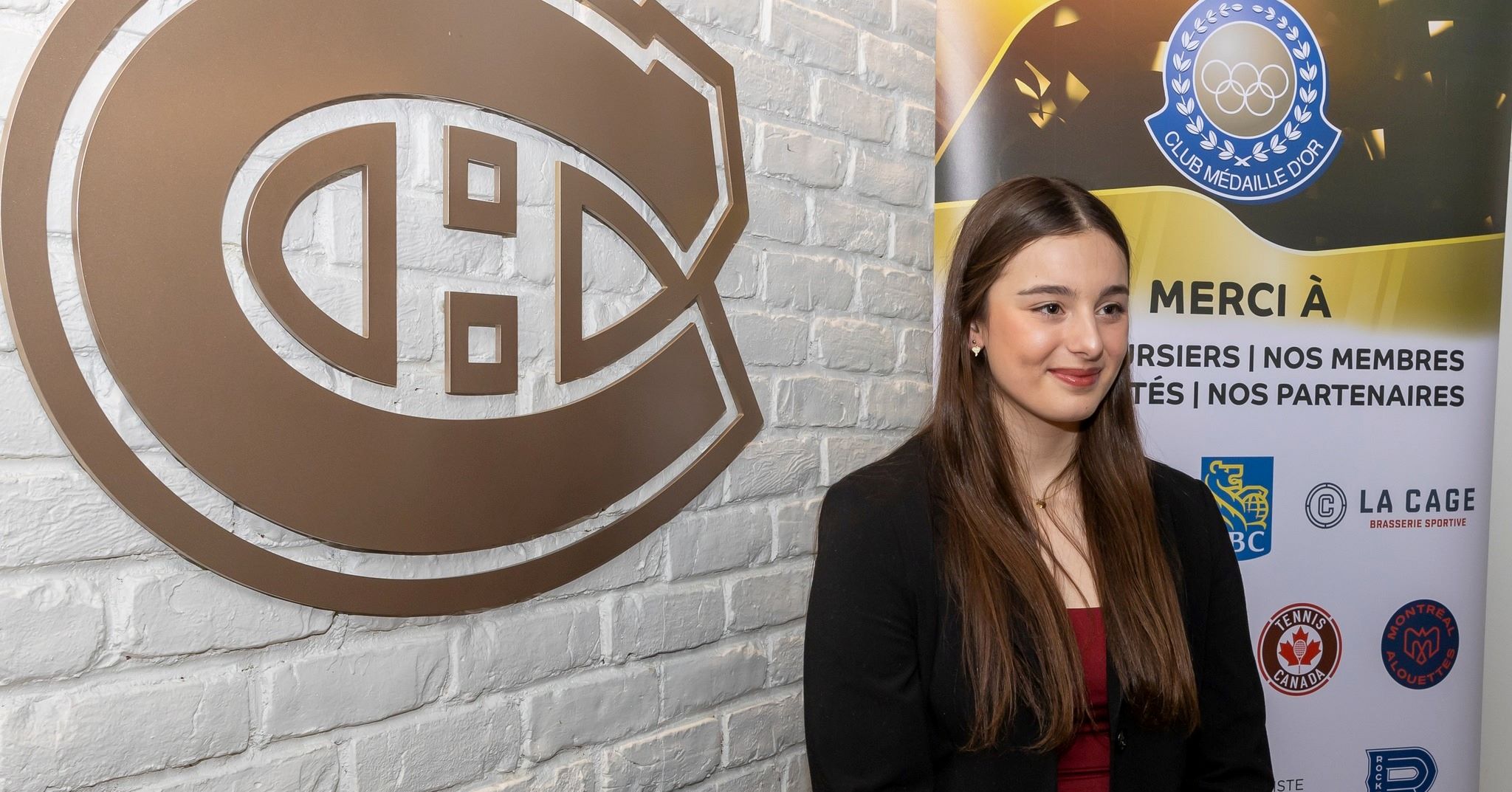 Florence se tient devant un mur avec le logo du Canadien de Montréal et elle sourie à la caméra. 