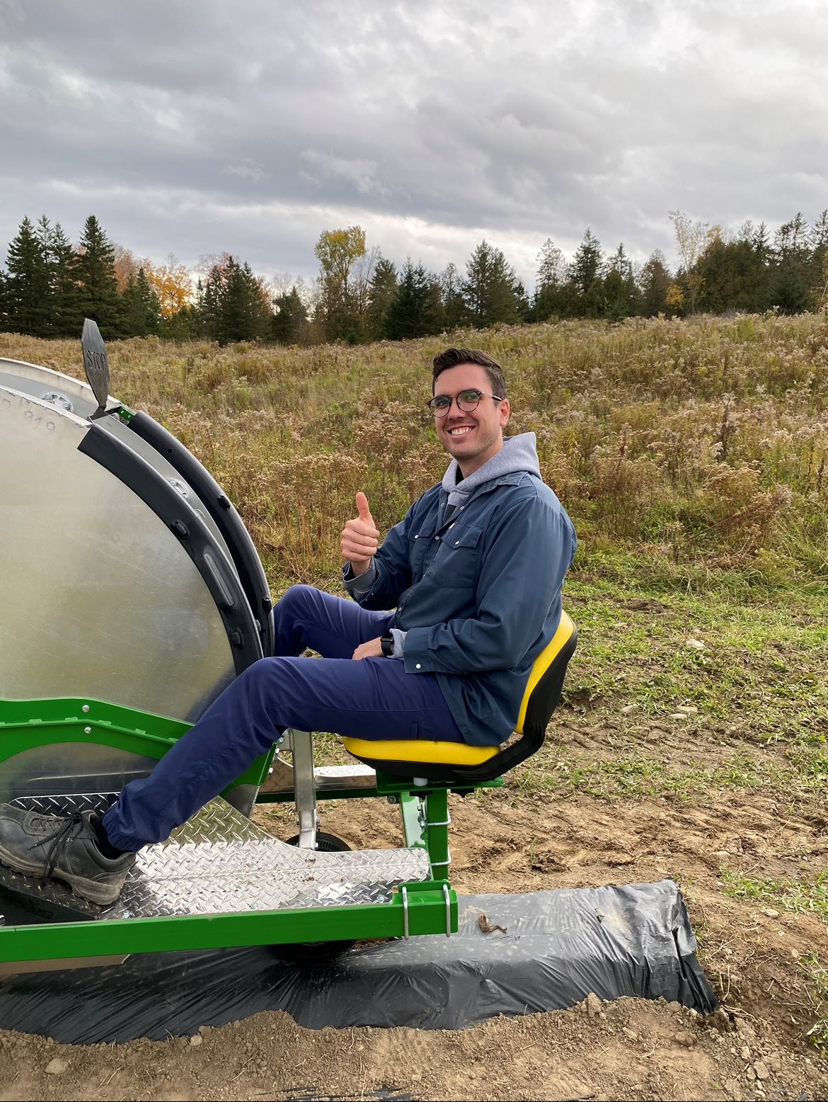 William Leclerc, diplômé en Génie mécanique, assis et souriant sur une transplanteuse à fraises conçue par son entreprise InnovaPlant