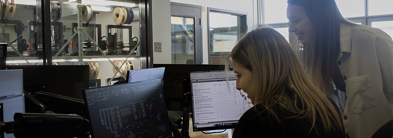 Deux étudiantes devant des écrans d'ordinateur dans un contexte industriel